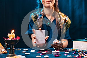Magic and esotirism concept. Smiling fortune-teller shows an empty white tarot card. Cartomancy and fortune telling photo