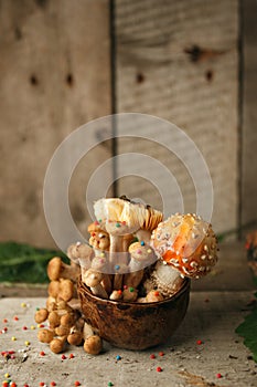 Magic fairytale party table decor, mushroom with confectionary in cup on wooden background, poison toxic food, halloween holiday.