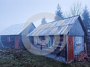 Magic fog in a fairy forest in warm autumn and two small wooden houses.