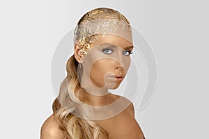 Magic girl portrait with gold skin. Golden creative makeup, close-up portrait in studio shot, color