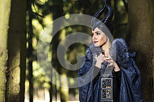 Magic Maleficent Woman Clothing and Horns in Spring Forest. Holding Lamp in Hand
