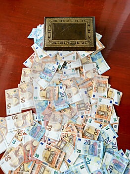 Magic old box overflowing with euro bank notes, european money fifty and twenty euros bills