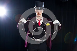 Magic, performance, circus, show concept - magician in top hat showing trick with linking rings