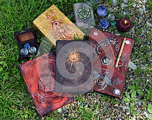 Magic ritual with decorated grimoire books, candles and witch objects on the grass