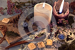 Wooden runes, healing herbs, black and white candles and diary book on lace napkin photo