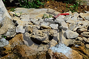 Magic water tap with red lever - looking like it is levitating in air, actually it is connected with rock via transparent hose