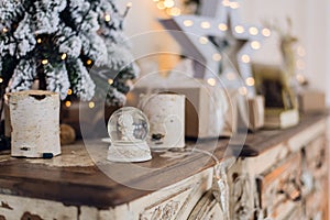 Magical Christmas snow globe with little angel statue inside. Christmas decoration around. Shallow depth of field with