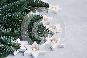 Magical Christmas theme: cozy, warm lights, garland, stars and fir branches on the grey background