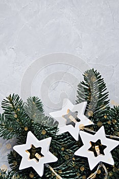 Magical Christmas theme: cozy, warm lights, garland, stars and fir branches on the grey background