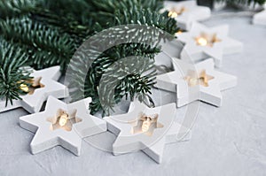 Magical Christmas theme: cozy, warm lights, garland, stars and fir branches on the grey background