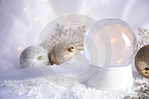 Magical empty snow globe with Christmas decorations on white fabric.