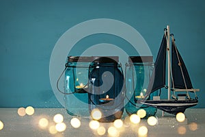 Magical mason jars whith candle light and wooden boat on the shelf