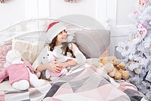 Magical morning. Sweet home. Girl little kid relaxing on bed light interior with christmas decorations. Cozy room. Small