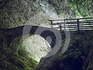 Magical old bridge,by night, light behind.