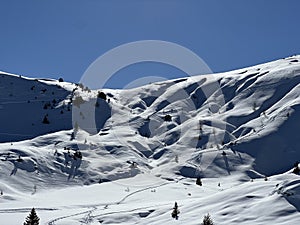 A magical play of sunlight and shadow during the alpine winter on the snowy slopes above the mountine resort of Arosa