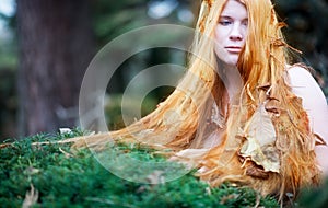 Magical redhead portrait of a young beautiful sexy woman, the long red hair full of autumn leaves, copy space