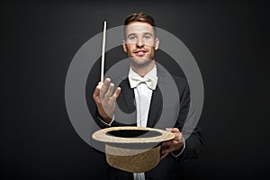 A magician in a black suit holding an empty top hat