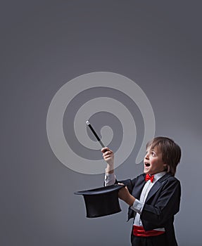 Magician boy performing with magic wand and hard hat