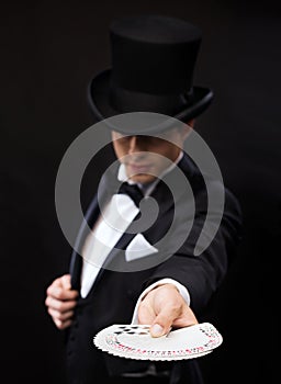 Magician in hat showing trick with playing cards