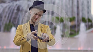 Magician in hat and yellow jacket skillfully moving playing cards in hands