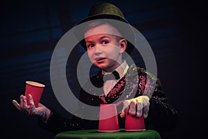 Magician kid illusionist boy in hat. childhood isolated black background