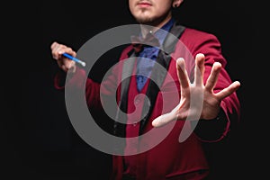 Magician man with magic wand on black background
