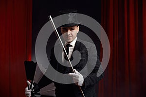 Magician performing miracle trick on stage using fan and cane