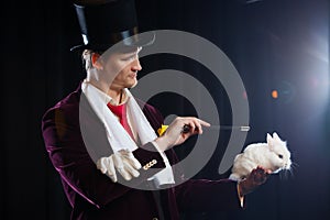 Magician with rabbit, juggler man, funny person, black magic, illusion on a black background