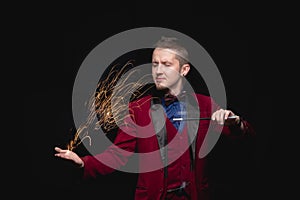 Magician shows focus fire with magic wand and sparks in his hands
