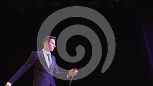 A magician shows a trick with a painted flower. The magician shows the focus with the appearance of flowers.