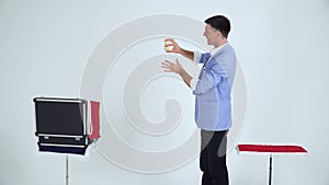 Magician in a suit shows a trick with balls on a white background