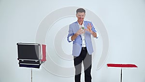 Magician in a suit shows a trick with balls on a white background