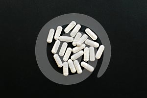 Magnesium capsules on black dark background. Flat lay. Dietary supplements. White pill. Health support and treatment. Biologically photo