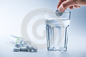 Magnesium pills and cup of clear water on blue white background photo