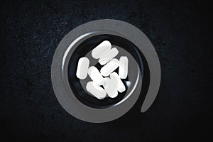 Magnesium tablets on dark stone background. Top view.