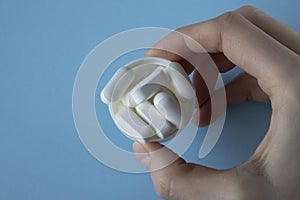 Magnesium Tablets. White tablets with rounded edges in a lid in a woman& x27;s hand on a blue background.