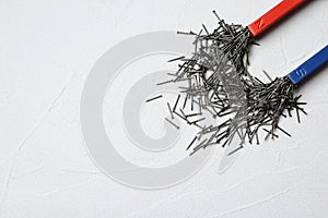 Magnet attracting nails on light background, top view