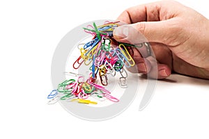 Man hand holding magnet attracting metal paper clips