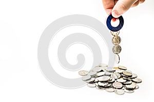 Magnet in a male`s hand attracting money from the coin pile on white background