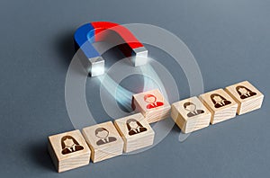 The magnet pulls a red person figure out of the row. Luring concept. Hiring best candidate. Poaching participants photo