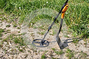 Magnetic metal detector and shovel for searching for precious metals and coins against the background of a path in a