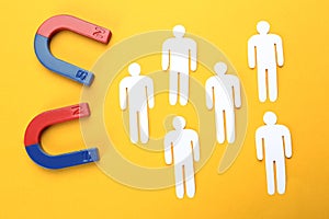 Magnets attracting people traffic on color background, top view.