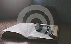 Magnification glass over a opened book in the dark room