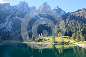 Magnificent autumn scenery of Lake Gosausee with rugged rocky mountain peaks in the background and beautiful reflections on water