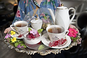 Magnificent fresh hot tea in ancient cups on a silver vintage tray and a raspberries dessert, an antique teapot