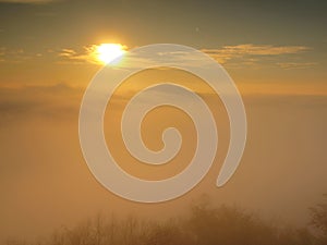 Magnificent heavy mist in landscape. Autumn fogy sunrise in a countryside. Hill increased from fog, the fog is colored to orange