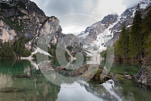 Magnificent lake Lago di Braies. The emerald smooth surface of water reflects the wood and mountains around photo