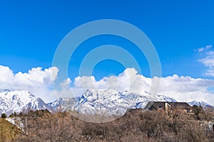 Magnificent mountain coated with snow against a vivid sky with puffy clouds