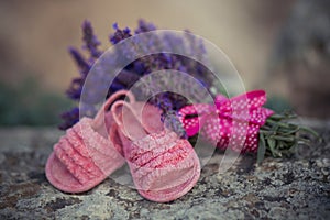 Magnificent picture of little baby girl pink shoes sandals close to lavender bouquet with pinky silk strap line on rocky stone.Awa photo