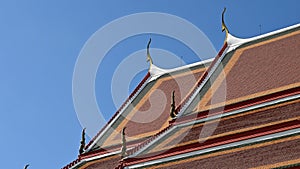 Magnificent roof in a Thai temple. The intricate details of traditional Thai temple roofs contrast with blue sky.